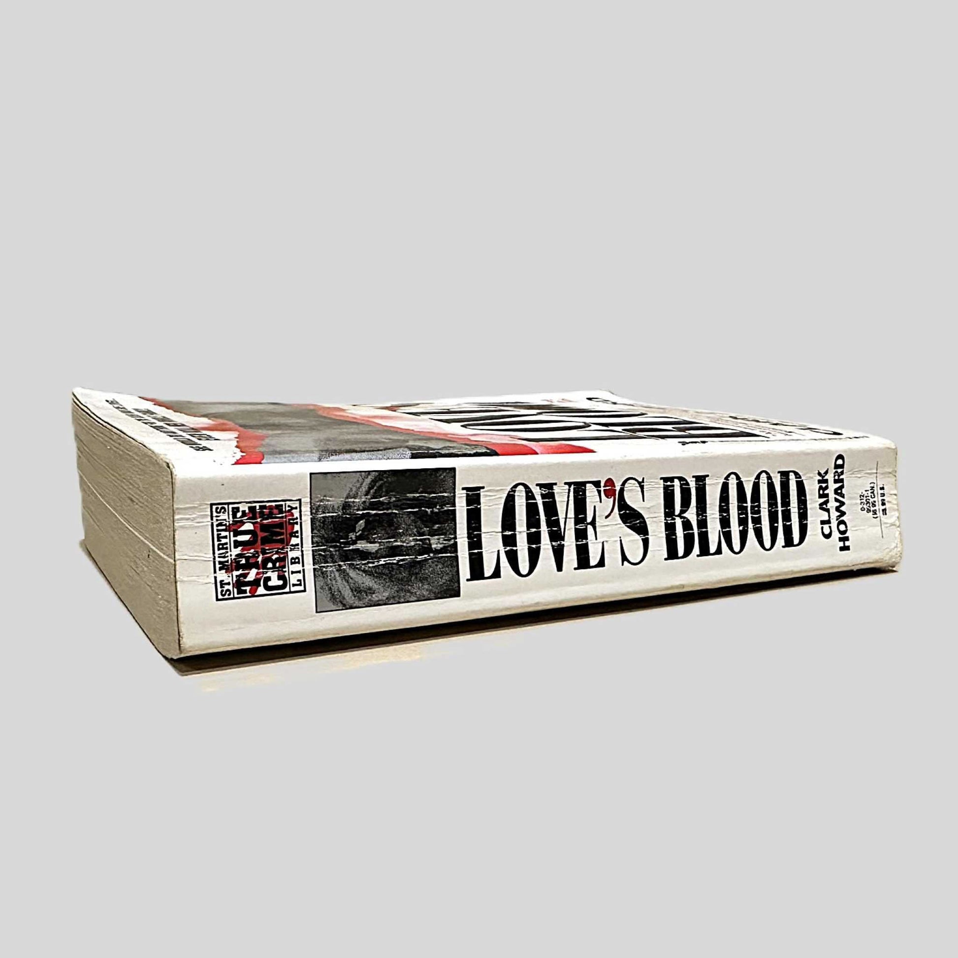 Close-up spine view of Love's Blood by Clark Howard centered on a neutral light gray background. Spine has visible creasing.