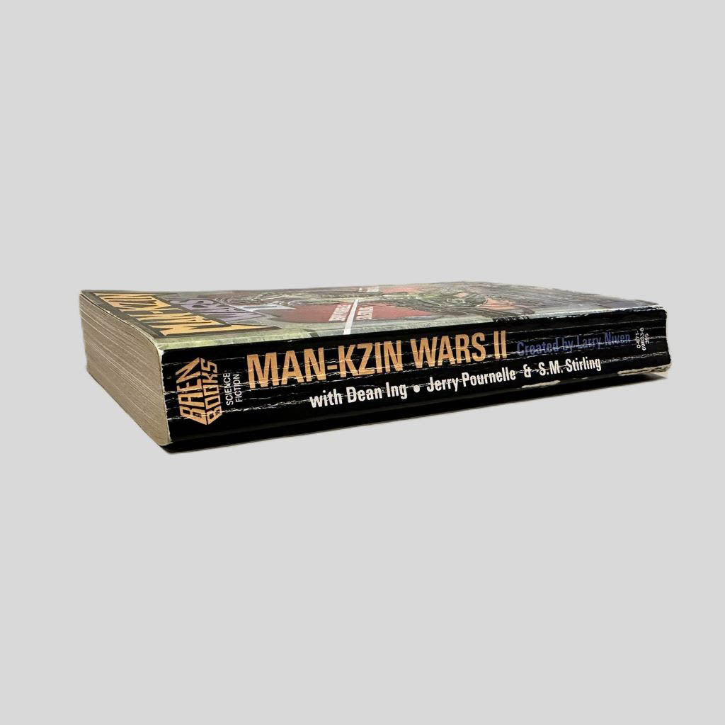 Close-up spine view of Man-Kzin Wars II by Larry Niven centered on a neutral light gray background. Spine shows creasing and chipping at the bottom end. Pages lay flat.