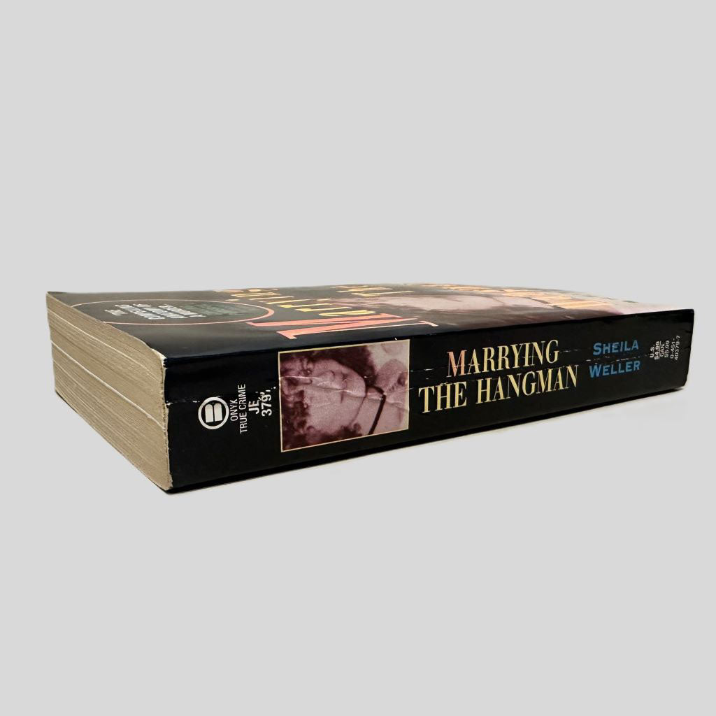 Close-up spine view of Marrying the Hangman by Sheila Weller centered on a neutral light gray background. Spine is square with minimal creasing. 