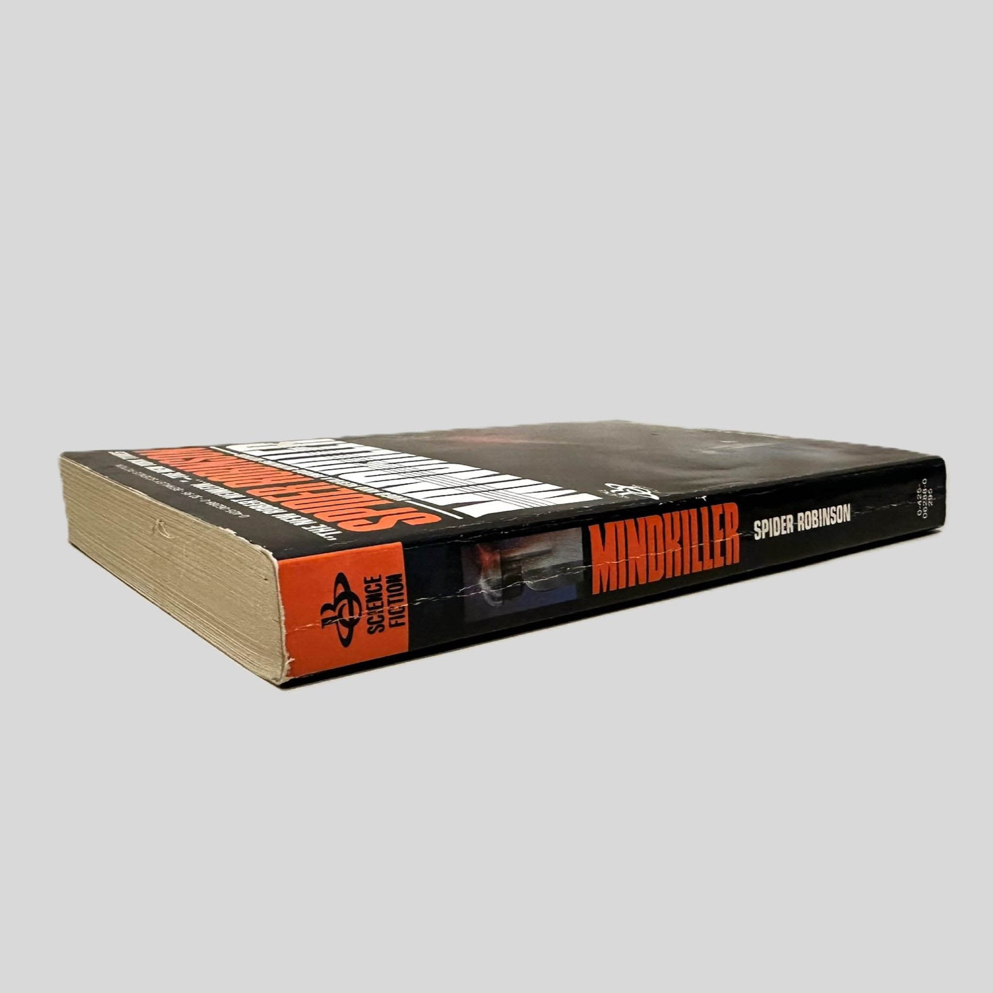 Close-up spine view of Mindkiller by Spider Robinson centered on a neutral light gray background. Spine is square and shows minor creasing. Pages lay flat.