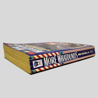 Close-up spine view of More Whatdunits by Mike Resnick ED centered on a neutral light gray background. Spine shows creasing. Pages lay flat.