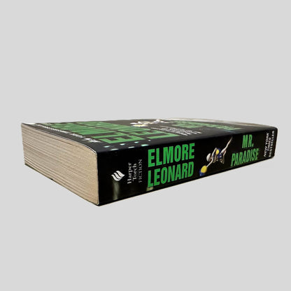 Close-up spine view of Mr. Paradise by Elmore Leonard centered on a neutral light gray background. Spine shows no creasing. Pages lay flat.