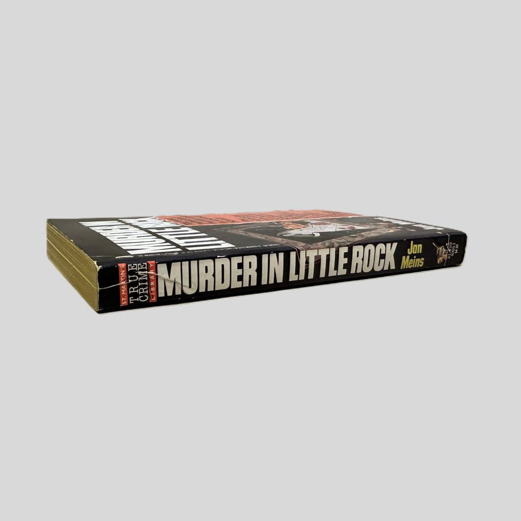 Close-up spine view of Murder in Little Rock by Jan Meins centered on a neutral light gray background. Spine is square with minimal creasing. 