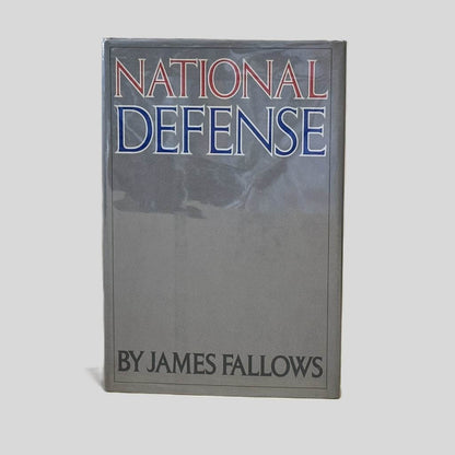 Front cover view of National Defense by James Fallows centered on a neutral light gray background. Dust jacket is present and shows no damage.