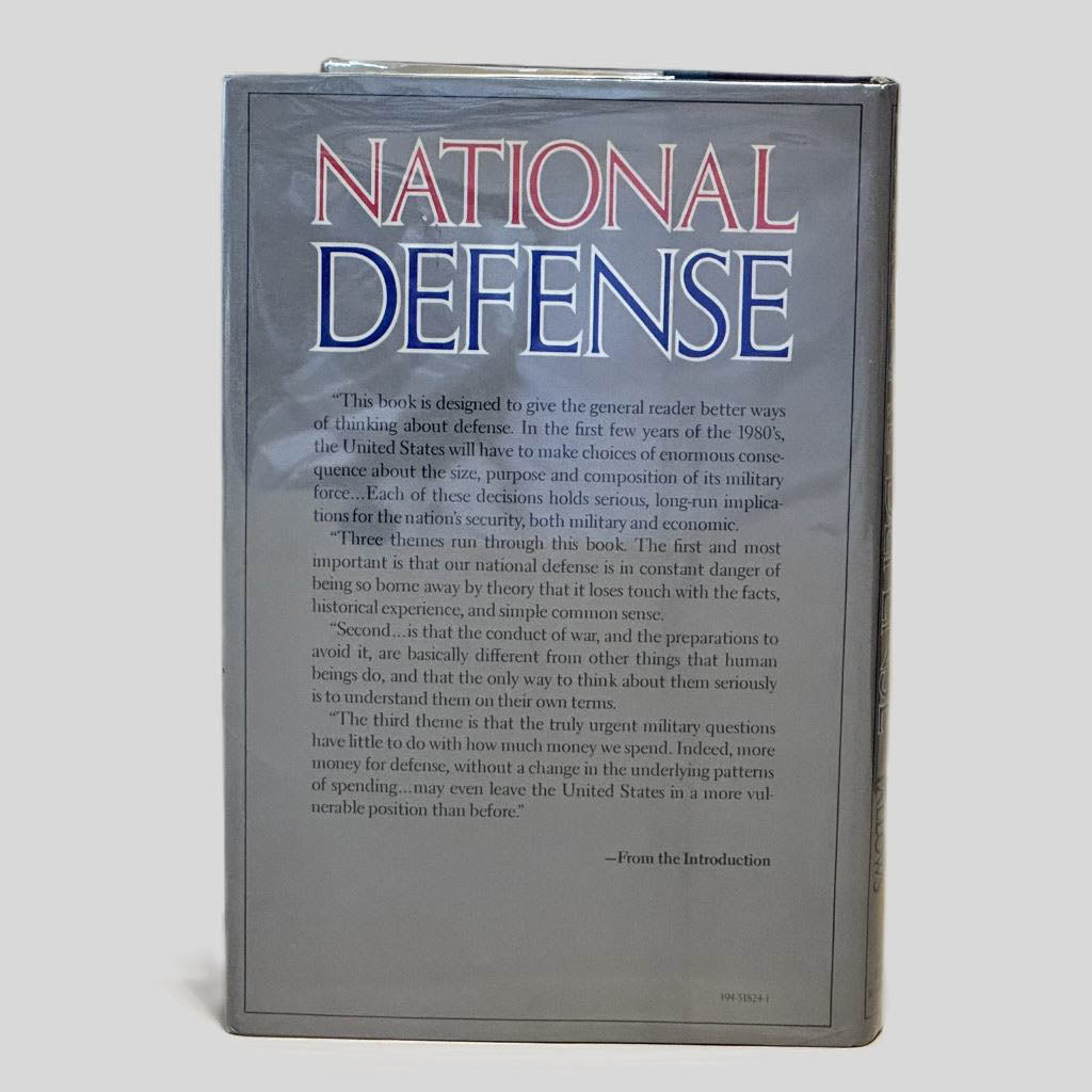 Back cover view of National Defense by James Fallows centered on a neutral light gray background. Dust jacket is present and shows no damage.