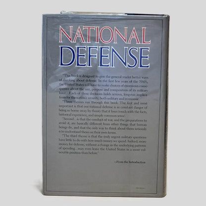 Back cover view of National Defense by James Fallows centered on a neutral light gray background. Dust jacket is present and shows no damage.
