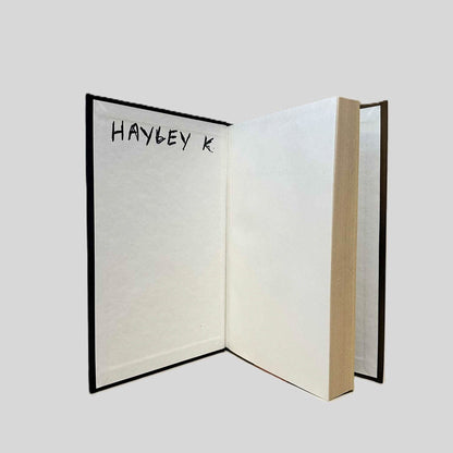 Inside front cover view of No Broken Hearts by Sheila York centered on a neutral light gray background. The name "HAYLEY K." is written in black ink on the inside front cover. Pages are straight and crisp.