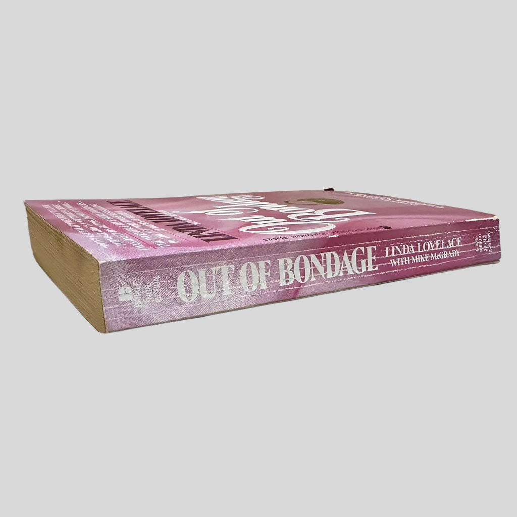 Close-up spine view of Out of Bondage by Linda Lovelace centered on a neutral light gray background. Spine shows creasing.