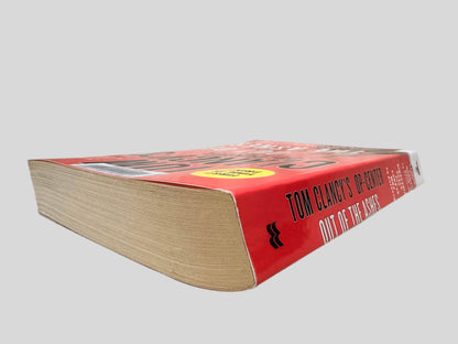 Close-up spine view of Out of the Ashes by Tom Clancy centered on a neutral light gray background. Spine shows no creasing. Pages lay flat.