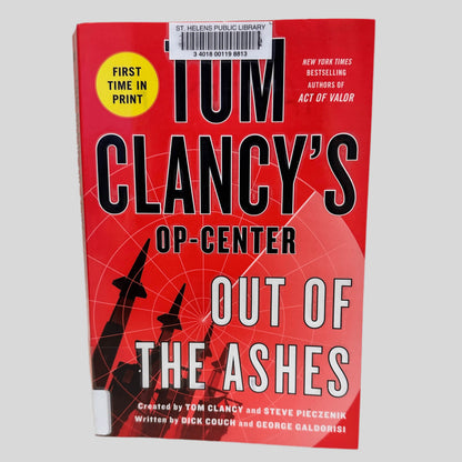 Front cover view of Out of the Ashes by Tom Clancy centered on a neutral light gray background. St. Helens Public Library barcode sticker is present, centered at the top of the book, covering part of the author's name. 