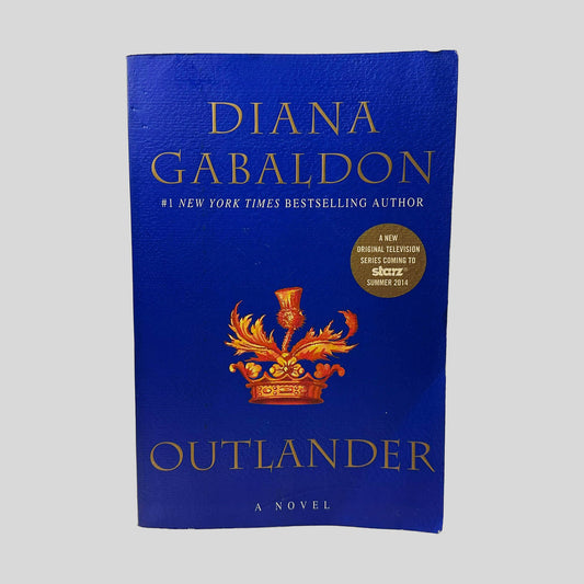 Front cover view of Outlander by Diana Gabaldon centered on a neutral light gray background. Minor chipping near corners. A slight wave is present. Cover art is vibrant.
