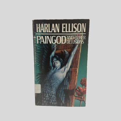 Front cover view of Paingod and Other Delusions by Harlan Ellison centered on a neutral light gray background. Creasing near the spine. Minor chipping around the edges. Cover art is vibrant.