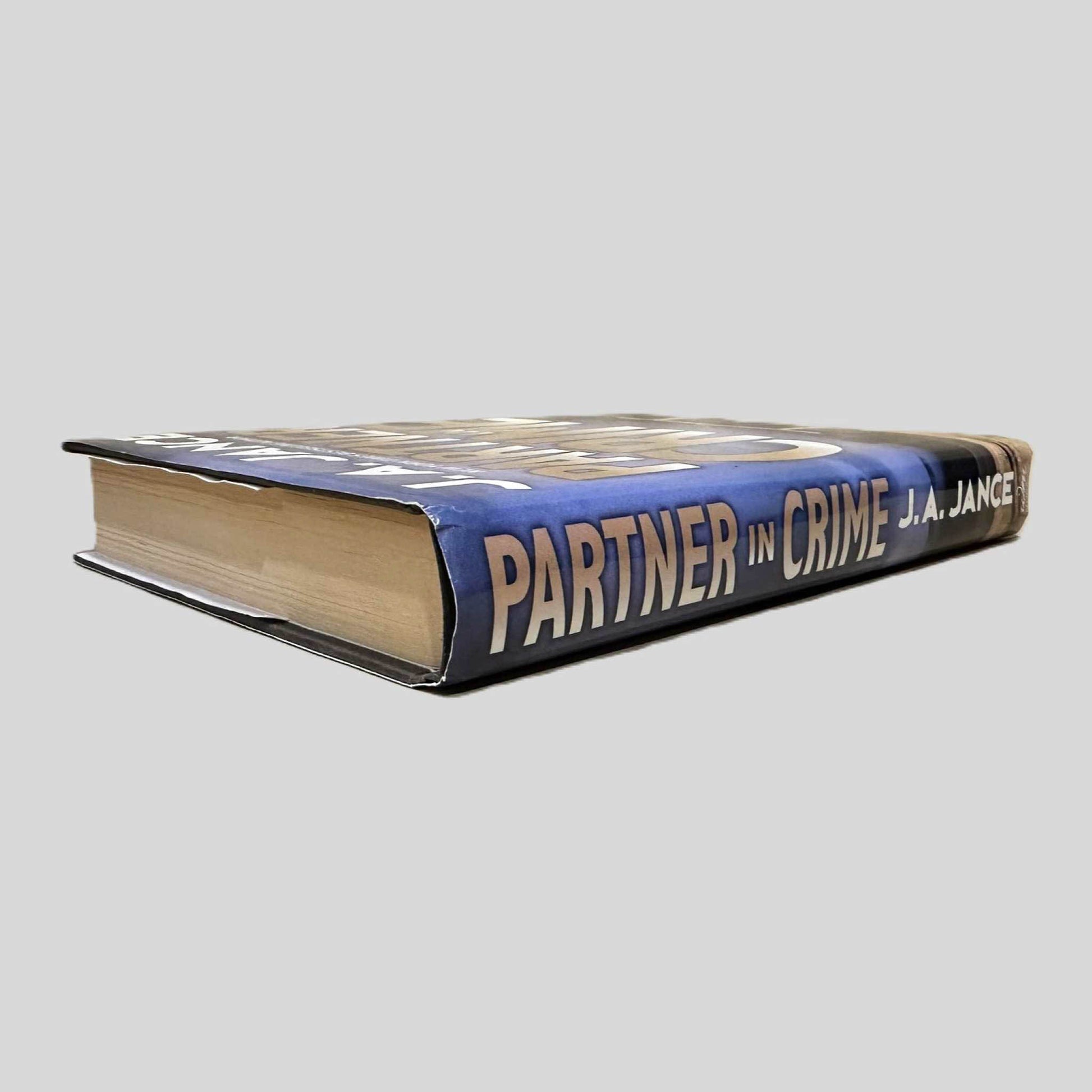 Close-up spine view of Partner in Crime by J.A. Jance centered on a neutral light gray background. Dust jacket is present and undamaged.  Pages lay flat.