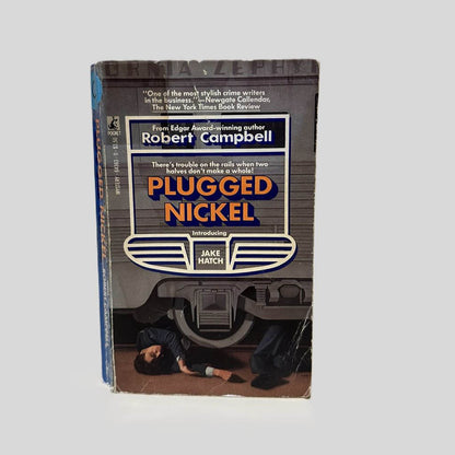 Front cover view of Plugged Nickel by Robert Campbell centered on a neutral light gray background. Creasing on the right bottom corner. 