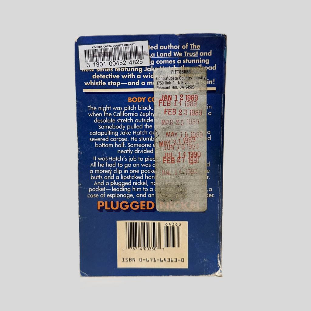 Back cover view of Plugged Nickel by Robert Campbell centered on a neutral light gray background. Library barcode sticker in the top left corner with black ink over it. There is also a long rectangular sticker with check out dates stamped in red ink on it from 1989 and 199. Chipping is present.