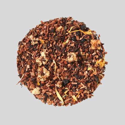 Plum Deluxe "Self Care" loose-leaf herbal tea featuring honeybush, elderberries, dried apricot pieces, and marigold petals arranged in a circle on a neutral background.