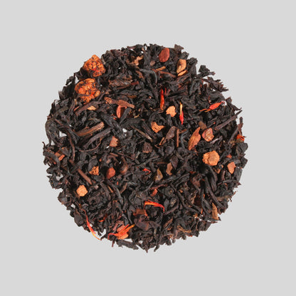 Plum Deluxe "Soul Warmer" loose-leaf herbal tea featuring red rooibos, dried chestnut pieces, and safflower petals arranged in a circle.