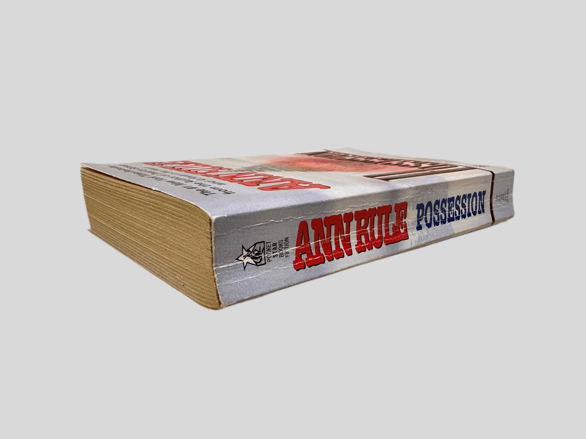 Close-up spine view of Possession by Ann Rule centered on a neutral light gray background. 