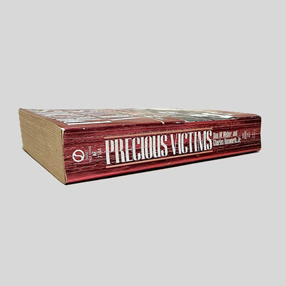 Close-up spine view of Precious Victims by Don W. Weber & Charles Bosworth, Jr. centered on a neutral light gray background. Spine shows creasing.
