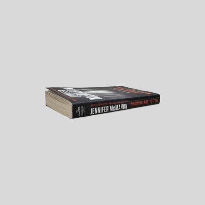 Close-up spine view of Promise Not To Tell by Jennifer McMahon centered on a neutral light gray background. 