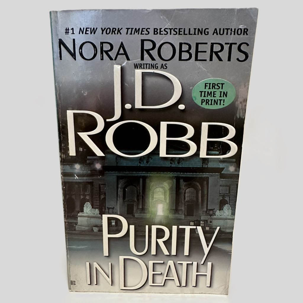 Front cover view of Purity in Death by J.D. Robb centered on a neutral light gray background. Creasing in the top right corner of the front cover.