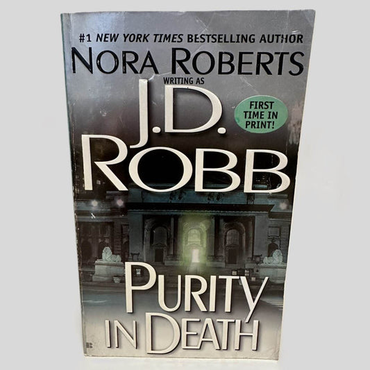 Front cover view of Purity in Death by J.D. Robb centered on a neutral light gray background. Creasing in the top right corner of the front cover.