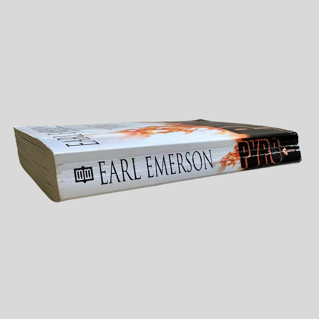 Close-up spine view of Back cover view of Pyro by Earl Emerson centered on a neutral light gray background. Spine shows creasing and cocking. 