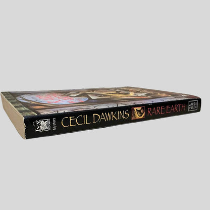 Close-up spine view of Rare Earth by Cecil Dawkins centered on a neutral light gray background. Spine is square and shows no creasing.