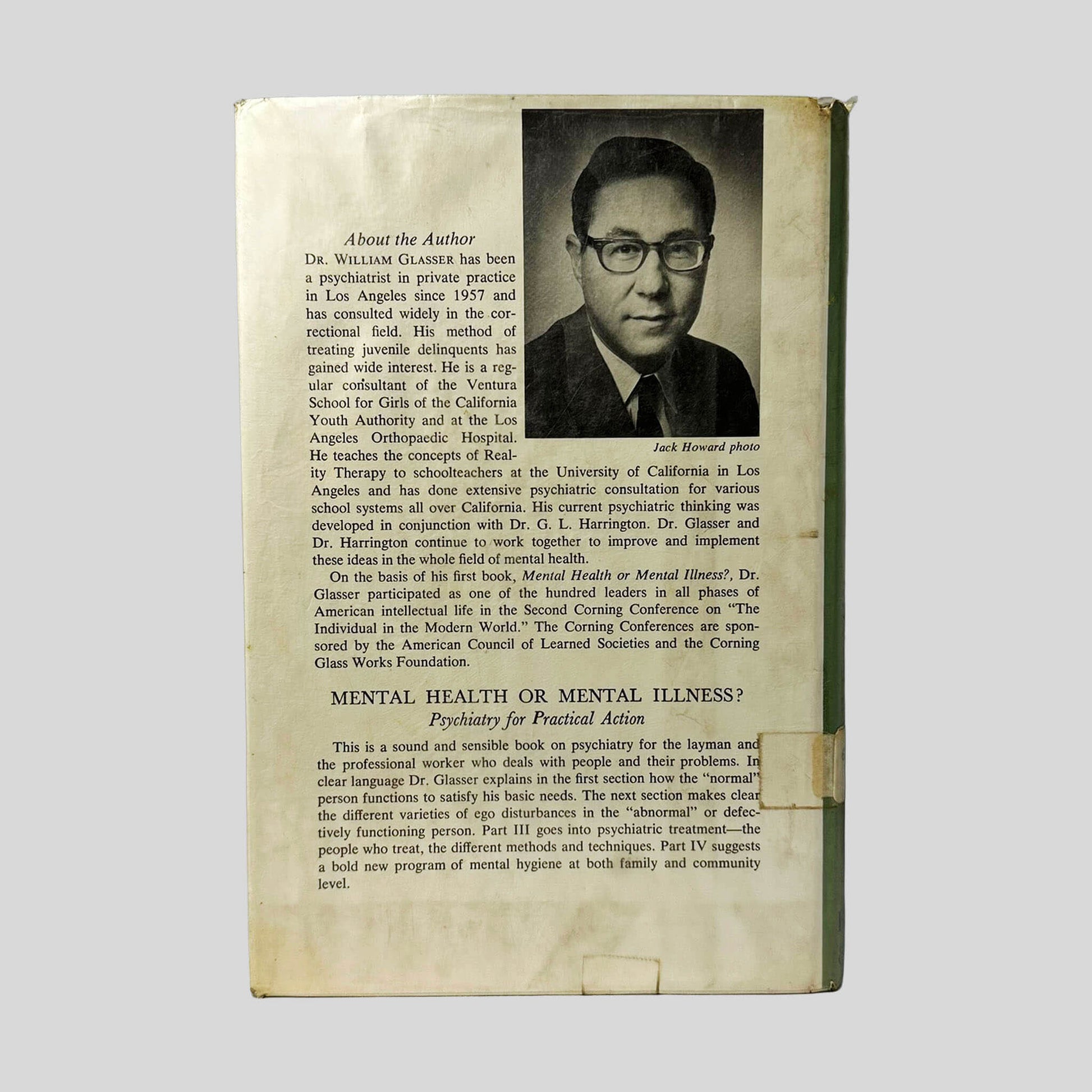 Back cover view of Reality Therapy by William Glasser, M.D. centered on a neutral light gray background. Dust jacket is present with library mylar cover. Fraying from wear to the jacket is present at the corners.