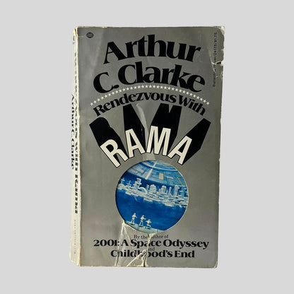 Front cover view of Rendezvous With Rama by Arthur C. Clarke centered on a neutral light gray background. Significant chipping to bottom center and top right edge. Additional chipping is present at the oop front of the spine corner.