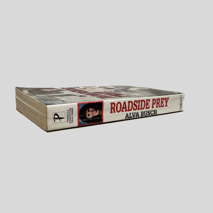 Close-up spine view of Roadside Prey by Alva Busch centered on a neutral light gray background. Spine is square and shows minimal creasing.