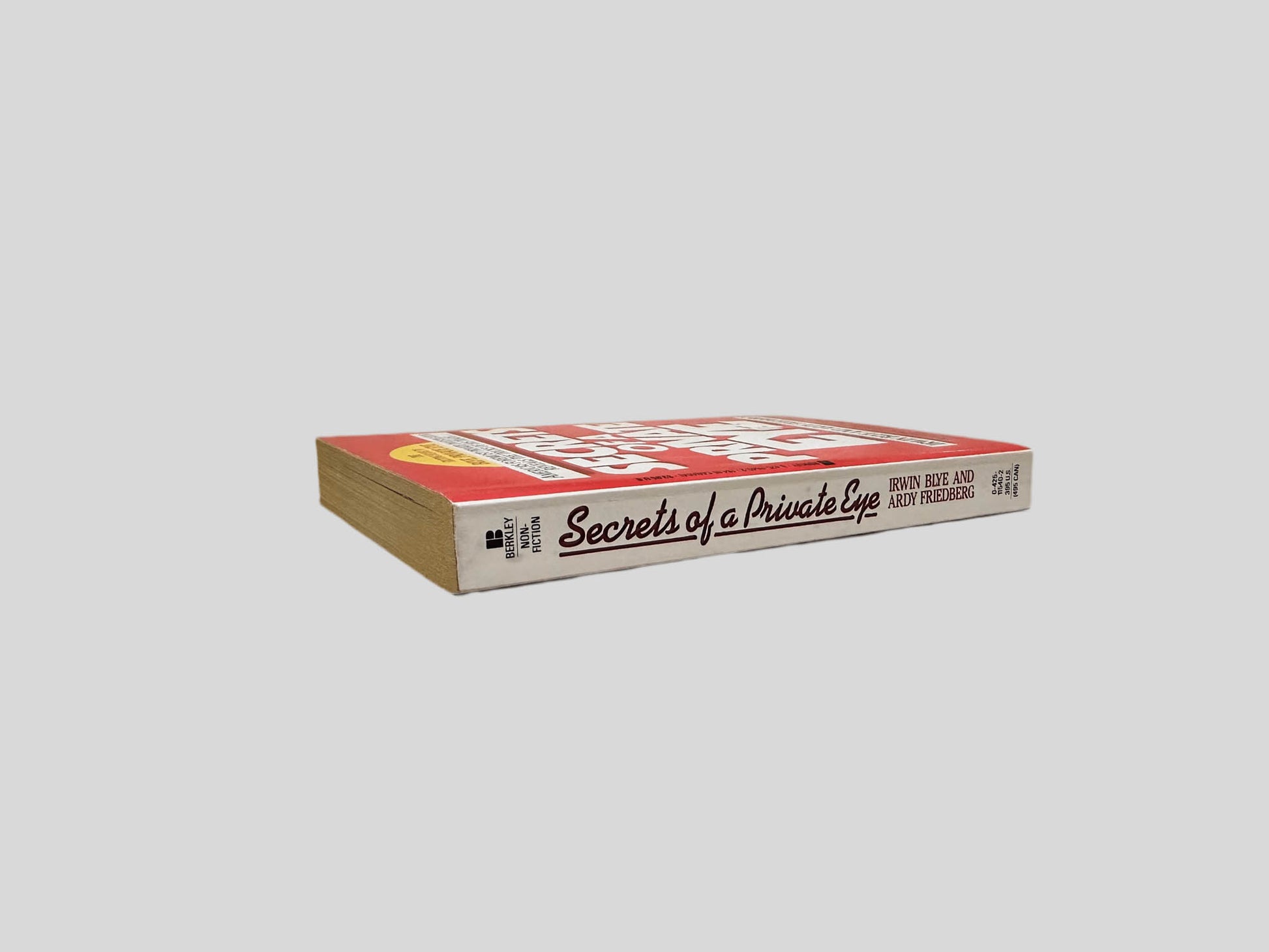 Close-up spine view of Secrets of a Private Eye by Irwin Blye & Ardy Friedberg centered on a neutral light gray background. Spine shows minimal creasing.