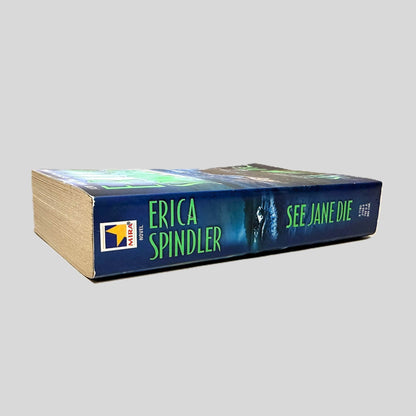 Close-up spine view of See Jane Die by Erica Spindler centered on a neutral light gray background. Spine shows minimal creasing. Pages lay flat.