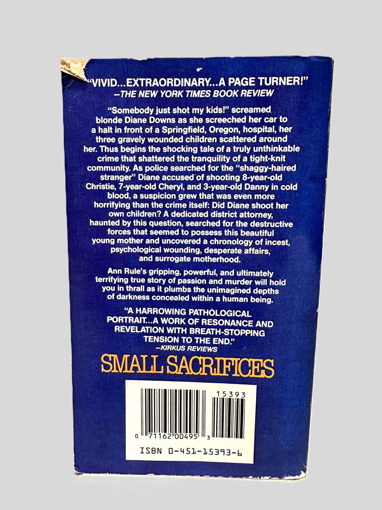 Back cover view of Small Sacrifices by Ann Rule centered on a neutral light gray background. Top corner as a small tear.
