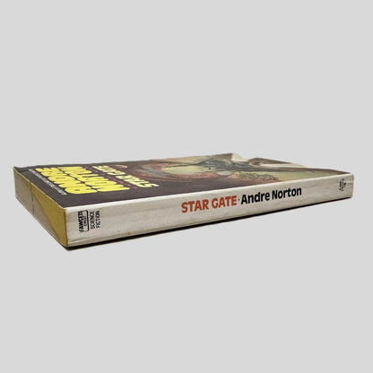 Close-up spine view of Star Gate by Andre Norton centered on a neutral light gray background. Spine shows minimal chipping and creasing. Pages lay flat.