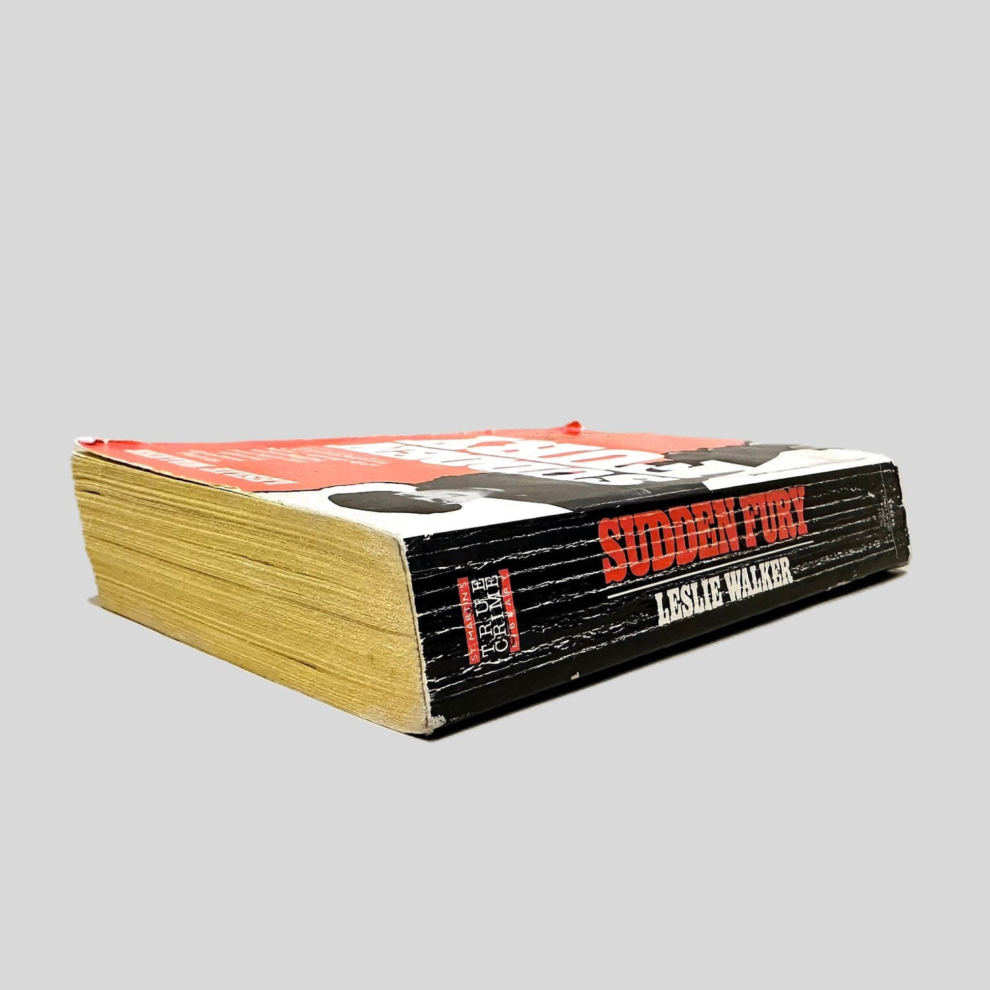 Close-up spine view of Sudden Fury by Leslie Walker centered on a neutral light gray background. Spine shows creasing and rubbing.