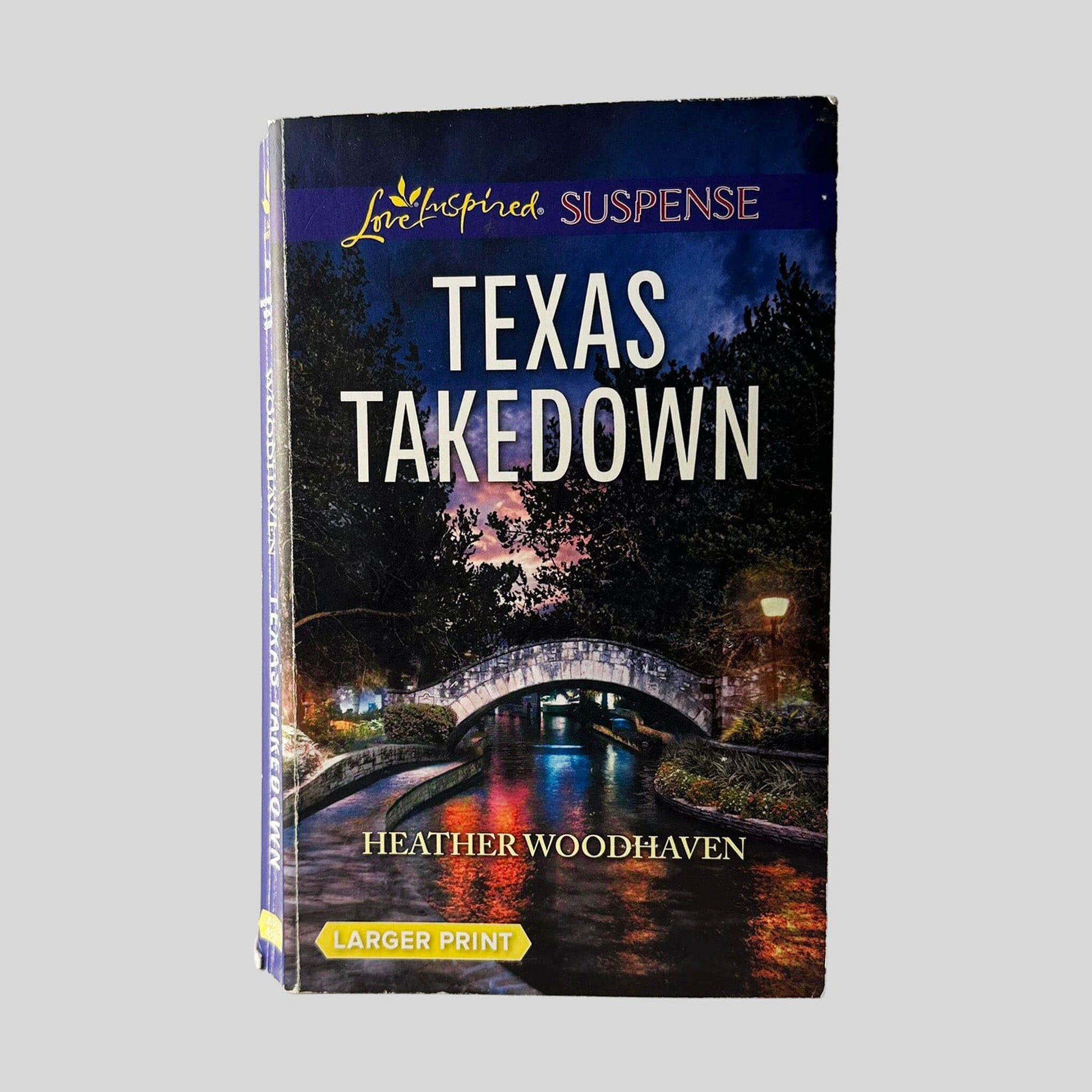 Front cover view of Texas Takedown by Heather Woodhaven centered on a neutral light gray background. Creasing near the spine edge. Chipping around the edges from general wear.