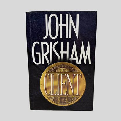 Front cover view of The Client by John Grisham centered on a neutral light gray background. Dust jacket is present and shows normal wear.