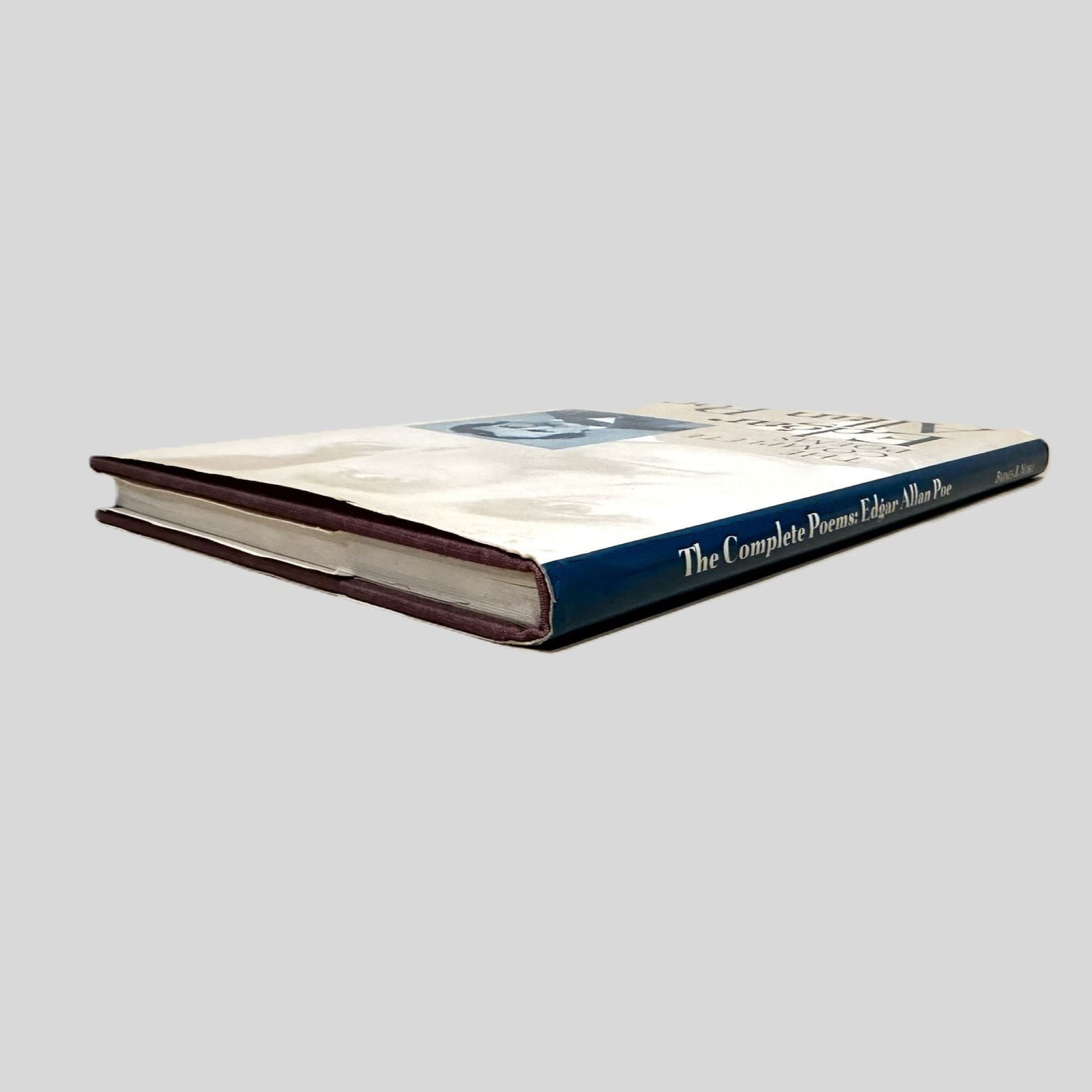 Close-up spine view of The Complete Poems of Edgar Allan Poe centered on a neutral light gray background. 