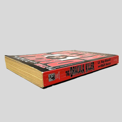 Close-up spine view of The Dracula Killer by LT. Ray Biondi & Walt Hecox centered on a neutral light gray background. Spine is square, shows creasing.