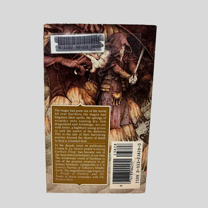 Back cover view of The Farthest Shore by Ursula K. Le Guin centered on a neutral light gray background. Minor chipping from age and normal wear along the top and bottom edges of the cover. Library barcode sticker in the top left corner, colored over with black ink. 