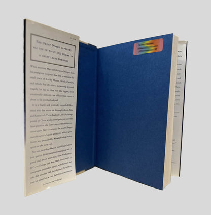 Inside front cover view of The Great Divide by T. Davis Bunn centered on a neutral light gray background. There is rainbow colored name/address sticker from a previous owner. The details are blurred out for privacy and safety of the previous owner.