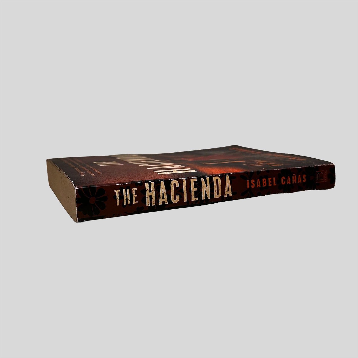 Close-up spine view of The Hacienda by Isabel Cañas centered on a neutral light gray background. 