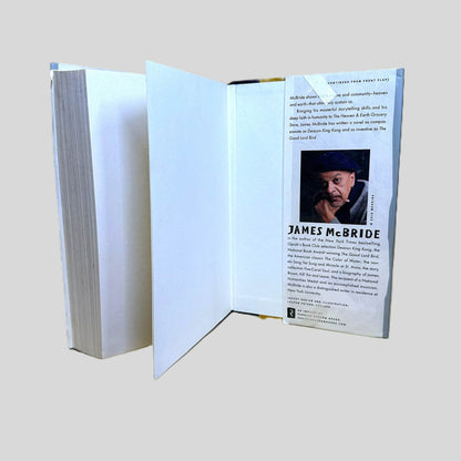 Inside back cover view of The Heaven and Earth Grocery Store by James McBride centered on a neutral light gray background. Pages are crisp and straight. 