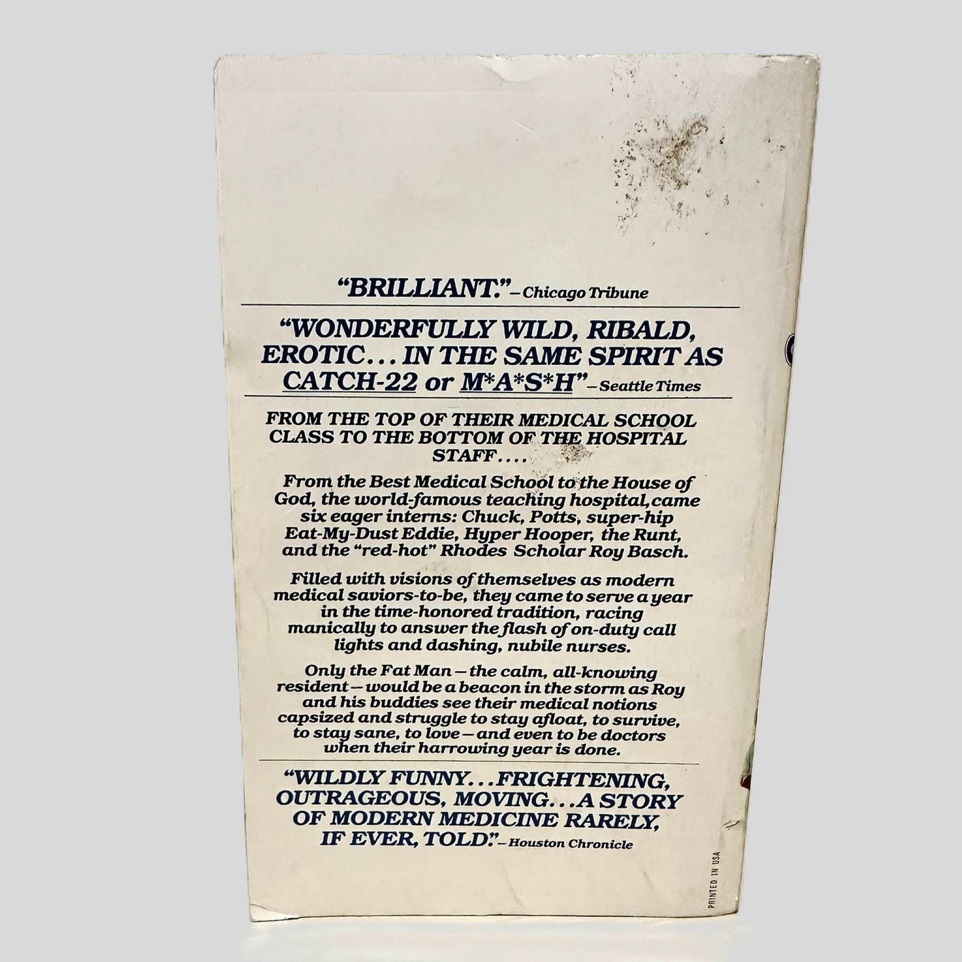 Back cover view of The House of God by Samuel Shem, M.D. centered on a neutral light gray background. Chipping and creasing around the edges. Staining on the top right corner.