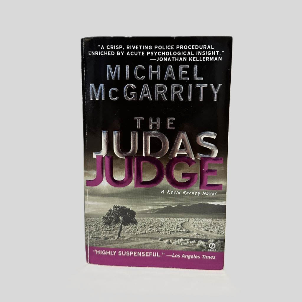 Front cover view of The Judas Judge by Michael McGarrity centered on a neutral light gray background. Minimal chipping along the top edge.
