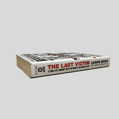 Close-up spine view of The Last Victim by Jason Moss centered on a neutral light gray background. Spine is square and shows minimal creasing.