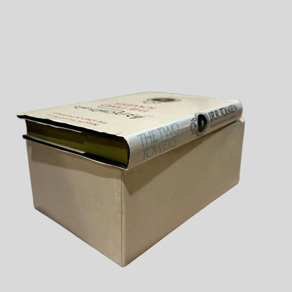 Empty slipcase for the 'The Lord of the Rings' paperback box set by J.R.R. Tolkien, showing 'The Two Towers' spine and green page edges. The dust jacket shows creasing at the top spine edge. Pages are tight and lay flat.