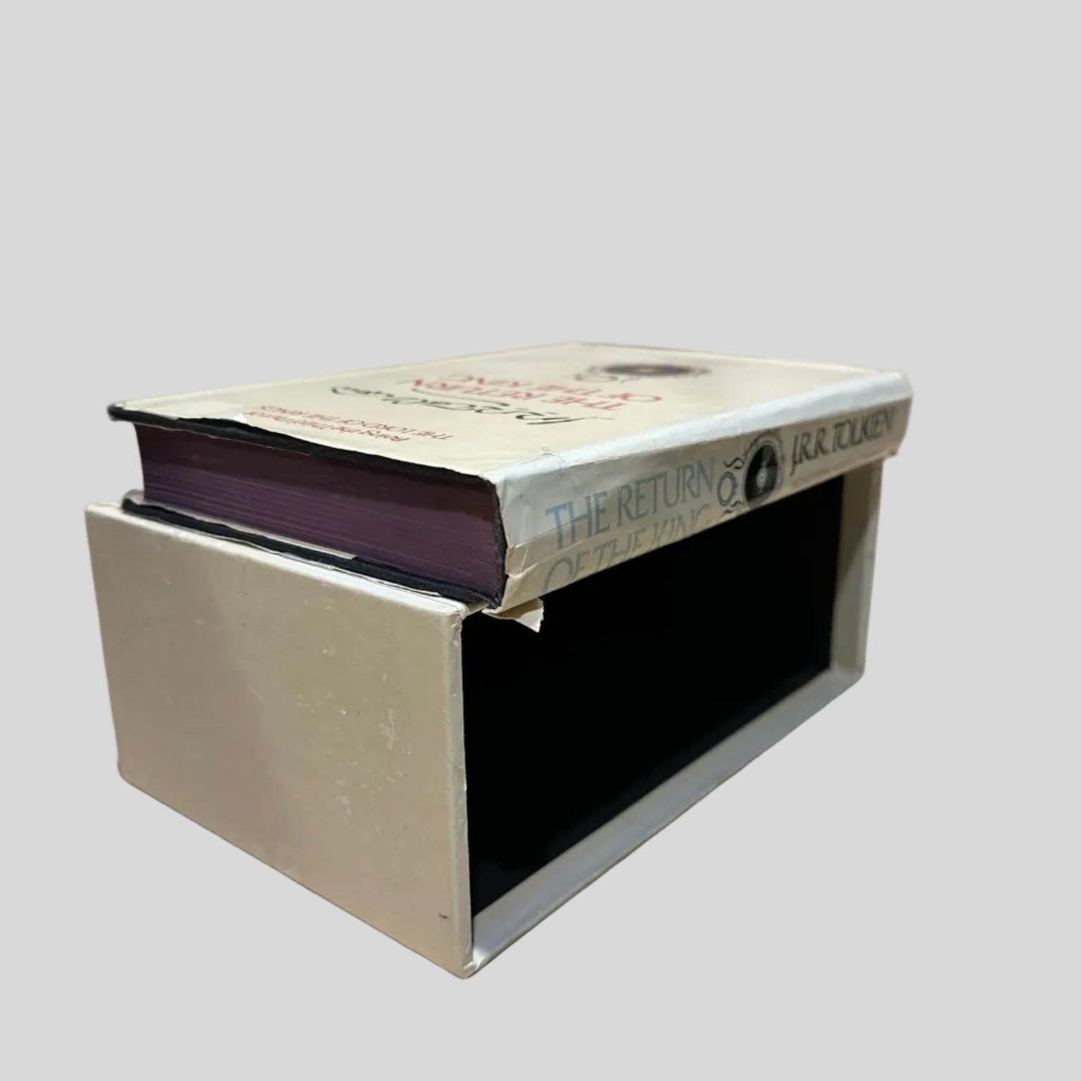 Angled view of the Lord of the Rings Revised Edition paperback 'The Return of the King' by J.R.R. Tolkien resting on top of its vintage white book-shaped slipcase. Dust jacket shows creasing along the spine edge. Pages are tight and lay flat.