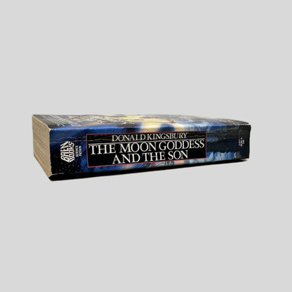 Close-up spine view of The Moon Goddess and the Son by Donald Kingsbury centered on a neutral light gray background. Spine shows minimal creasing. Pages lay flat.